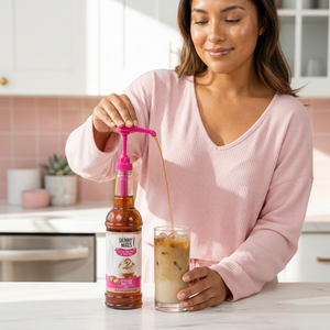 Woman pouring a drink from a skinny mixes syrup bottle into a glass.